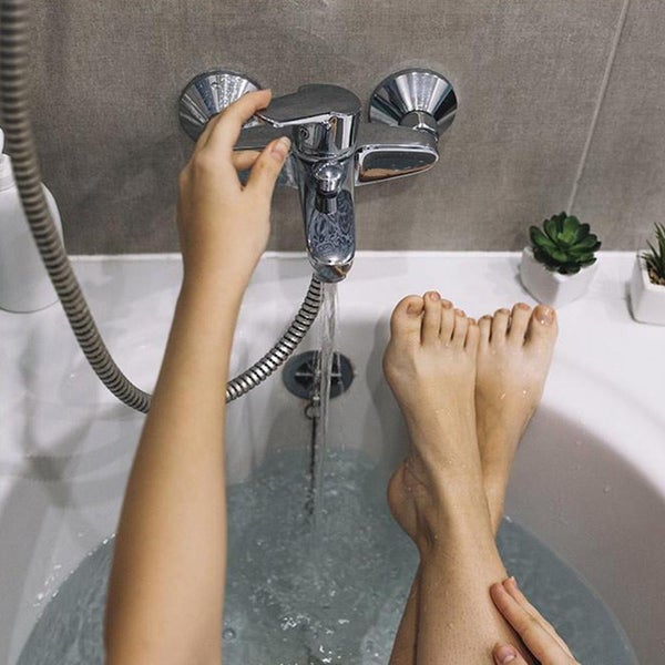 Bain avec main qui ouvre le robinet pour faire couler l'eau-Bodymania